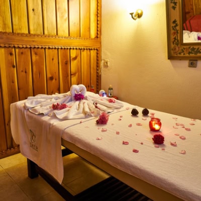 A hotel massage with lots of petals over the bed and towels.